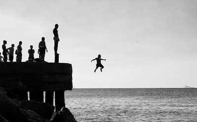 During the day, a man and a woman standing on the rocks on the beach
